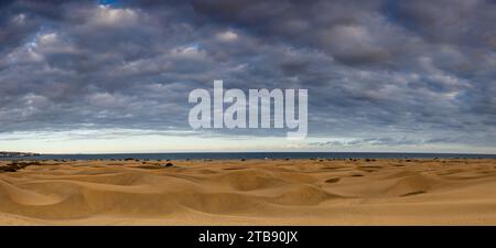 Natürliche Sanddünen von Maspalomas in der Nähe von Maspalomas, Spanien (Panoramablick) mit Wolken über den Dünen bei Sonnenuntergang. Stockfoto