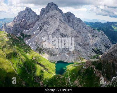 Aus der Vogelperspektive auf den Volaiasee, Wolayersee, an der Grenze zwischen Italien und Österreich mit dem Berg Coglians im Hintergrund. Bewölkter Tag mit Sonnenaufgang. Stockfoto