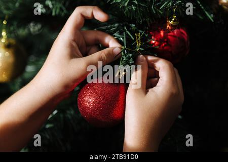 Der Junge, der den weihnachtsbaum in seinem Haus vor der Weihnachtsfeier zusammenstellt. Nahaufnahme der Hände. Stockfoto