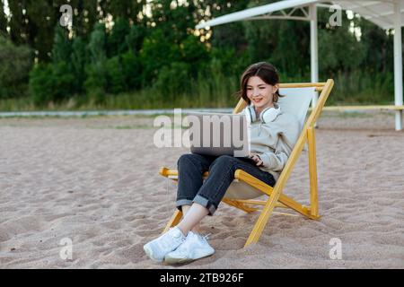 Glückliche Frau, die am Strand am Laptop arbeitet Stockfoto