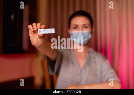 Nahaufnahme einer Frau in Schutzmaske mit Schnelltestgerät mit negativem COVID-19-Ergebnis zu Hause Stockfoto