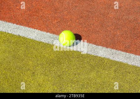 Grüner Tennisball auf der weißen Linie des Platzes Stockfoto
