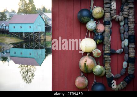 Bootshaus spiegelt sich im Wasser und Fischernetzschwaden und Bojen hängen an einer Tür; Petersburg, Alaska, Vereinigte Staaten von Amerika Stockfoto