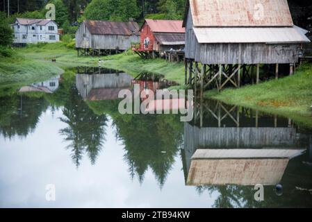 Alte hölzerne Bootshäuser auf Stelzen, die sich im Wasser spiegeln; Petersburg, Alaska, Vereinigte Staaten von Amerika Stockfoto