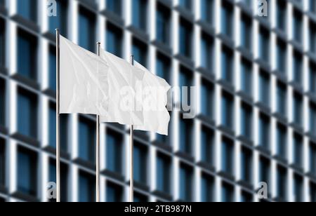 Drei weiße Firmenflaggen winken im Wind gegen verschwommenes Bürogebäude. Leeres Flag-Modell zum Hinzufügen eines Logos, Symbols oder Schildes Stockfoto