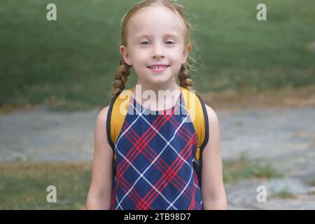 Blondes Schulmädchen mit gelbem Rucksack, strahlend Freude auf dem Weg zur Schule, zurück zur Schule Konzept Stockfoto