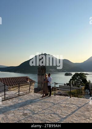 Perast, Montenegro - 03. august 2023: Mann und Frau auf einer Aussichtsplattform in der Nähe der Nikolaikirche. Perast, Montenegro Stockfoto