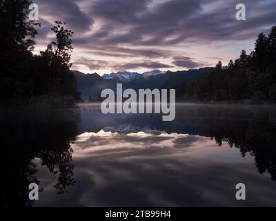 Sonnenaufgang am Lake Matheson mit Mount Tasman und Mount Cook in der Ferne; Fox Glacier, South Island, Neuseeland Stockfoto