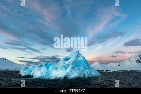 Eisberg und Sonnenaufgangshimmel um 4:30 Uhr morgens im antarktischen Sommer; Neumayer Channel, Antarktis Stockfoto