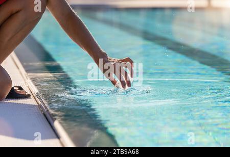 Halten Sie einen Behälter mit der Hand, um eine Wasserprobe aus einem Pool für einen pH-Test zu entnehmen Stockfoto