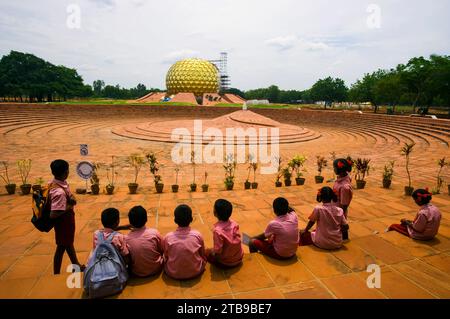 Schulkinder besuchen Auroville, die utopische „Stadt mit einer Seele“, mit Blick auf Matri Mandir in der Ferne; Auroville, Tamil Nadu, Indien Stockfoto