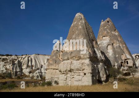 Höhlenhäuser, die aus Felsformationen vor einem hellblauen Himmel in der Nähe der Stadt Goreme im Pigeon Valley in der Region Kappadokien gemeißelt wurden Stockfoto