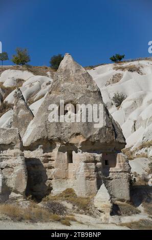 Nahaufnahme eines in die vulkanischen Felsformationen gehauenen Felsenhauses, eines Feenkamins, vor einem hellblauen Himmel in der Nähe der Stadt Goreme in Pigeon Val... Stockfoto