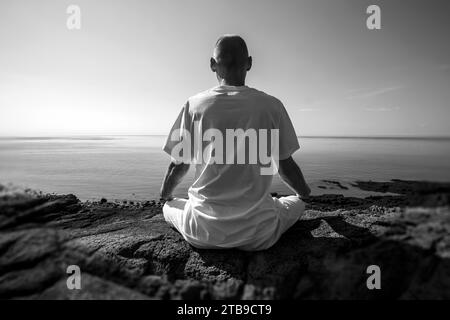 Mann, der in Lotus-Position am Atlantik meditiert; Digby, Nova Scotia, Kanada Stockfoto