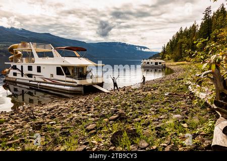 Eine Familie, die einen Hausbooturlaub genießt, während sie an der Küste des Shuswap Lake; Shuswap Lake, British Columbia, Kanada parkt Stockfoto