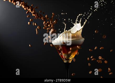 Espresso Martini-Getränk mit Spritzern und fallenden Kaffeebohnen auf schwarzem Hintergrund. Kopierbereich. Stockfoto