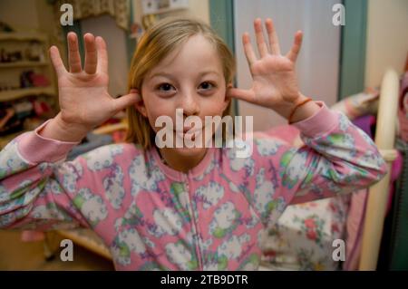 Mädchen in ihrem Schlafzimmer, das sich fürs Bett fertig macht und ein albernes Gesicht für die Kamera macht; Lincoln, Nebraska, USA Stockfoto
