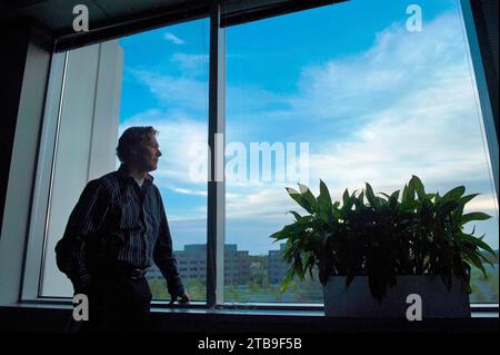 Ein Mann schaut aus einem Bürofenster; Chantilly, Virginia, USA Stockfoto