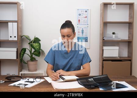 Arzt in blauer Uniform konzentriert sich auf Überprüfung medizinischer Dokumente und Testergebnisse, genaue Aufzeichnungen. Stockfoto