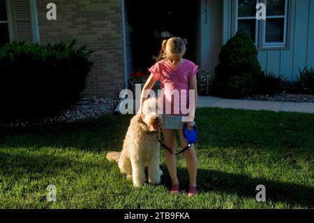 Das junge Mädchen spielt mit ihrem Haustier fanci Doodle in ihrem Garten; Elkhorn, Nebraska, Unied States of America Stockfoto