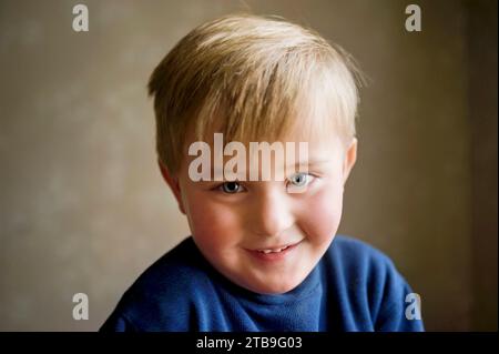 Kleiner Junge, der schüchtern lächelt; Studio Stockfoto