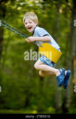 Junge schaukeln auf einer Schaukel; Cross Lake, Minnesota, Vereinigte Staaten von Amerika Stockfoto