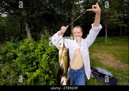 Frau zeigt mehrere Fische, die sie in einem See gefangen hat; Crosslake, Minnesota, Vereinigte Staaten von Amerika Stockfoto