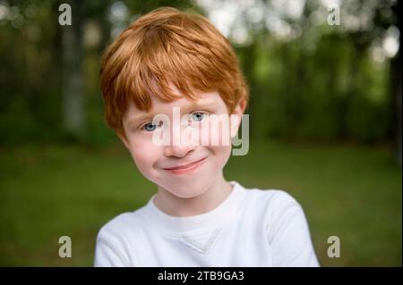 Nahaufnahme eines jungen Jungen mit roten Haaren und blauen Augen; Crosslake, Minnesota, USA Stockfoto