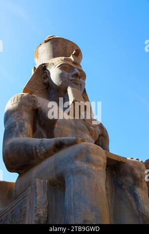 Nahaufnahme der Statue von Ramses II. Vor einem blauen Himmel vor dem antiken ägyptischen Tempel; Luxor, Ägypten Stockfoto