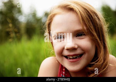 Porträt eines jungen Mädchens in einem Park, lächelnd; Edmonton, Alberta, Kanada Stockfoto