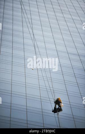 Person, die die Fenster eines Wolkenkratzers reinigt, der an einem Kletterseil hängt, Panama-Stadt, Republik Panama. Stockfoto