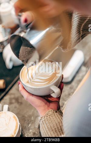 Eine Person, die eine frisch gebrühte Tasse heißen Kaffee in eine Tasse gießt Stockfoto