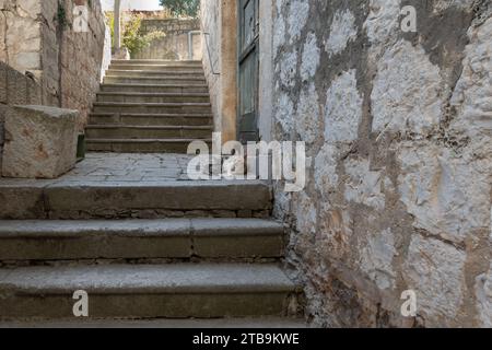 Zwei Katzen ruhen auf einer Treppe vor der Haustür eines traditionellen Wohnhauses aus Stein in der Stadt Vis in Kroatien Stockfoto