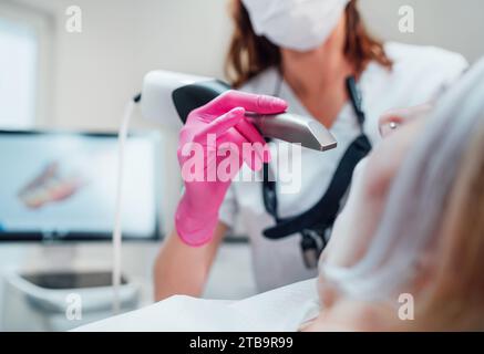 Zahnärztin in Uniform mit intraoralem 3D-Dentalscanner Maschine zur Herstellung klarer Aligner. Zahnärztliche Klinik Patientenbesuch moderne Medizin W Stockfoto