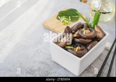 Gekochter Shiitake. Gekochte Shiitakes werden zum Marinieren zubereitet. Marinierte Shiitakes in einer quadratischen Schüssel. Kopierbereich. Stockfoto