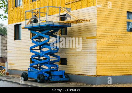 Der Einsatz eines Scherenhebers in Fassadenverkleidungen funktioniert nach dem Aufsprühen der Fassade mit Wärmedämmschaum Stockfoto