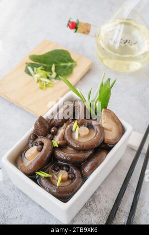 Gekochter Shiitake. Gekochte Shiitakes werden zum Marinieren zubereitet. Marinierte Shiitakes in einer quadratischen Schüssel. Stockfoto