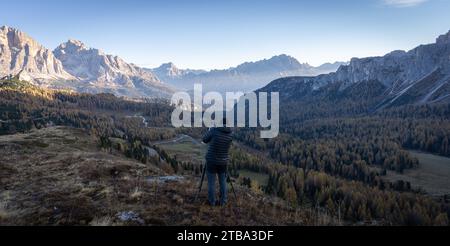 Fotograf mit Kamera auf einem Stativ, der während des Sonnenaufgangs in den Dolomiten Fotos vom wunderschönen Tal macht Stockfoto