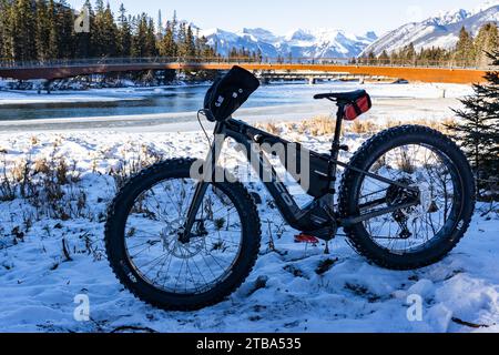 Banff Alberta Canada, 1. Dezember 2023: Ein feines Rad, das im Schnee geparkt ist und nach einer Schneebase eine Fußgängerbrücke und die kanadischen Rocky Mountains überblickt Stockfoto