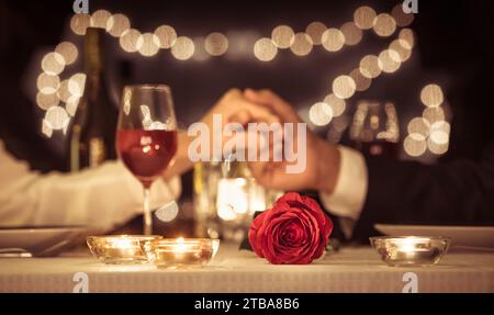 Datum Nacht. Mann und Frau, die Hände halten. Love and Dating Konzept. Konzentriere dich auf Rose. Stockfoto