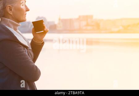 Eine Frau, Dame trinkt einen Kaffee und genießt den Sonnenuntergang. Stockfoto
