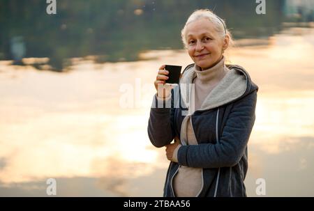Eine Frau, Dame trinkt einen Kaffee und genießt den Sonnenuntergang. Stockfoto