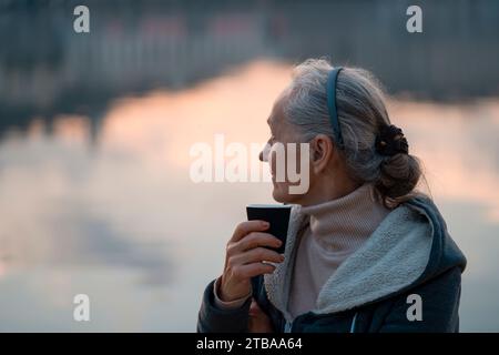 Eine Frau, Dame trinkt einen Kaffee und genießt den Sonnenuntergang. Stockfoto