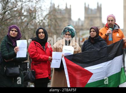 London, Großbritannien. Dezember 2023. Demonstranten halten die Namen einiger medizinischer Fachkräfte, die in Gaza getötet wurden, während ein anderer während einer Demonstration vor dem St. Thomas's Hospital eine palästinensische Flagge hochhält. Gesundheitspersonal versammeln sich vor ihrem Krankenhaus, St. Thomas, um Kollegen hervorzuheben, die während des Krieges im Gazastreifen gestorben oder vermisst wurden. Sie fordern einen dauerhaften Waffenstillstand. Quelle: SOPA Images Limited/Alamy Live News Stockfoto