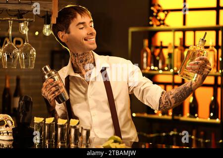 Junger Barkeeper mit Tequila und Shaker in der Bar am Abend Stockfoto