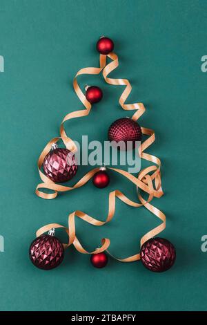 Weihnachtsbaum aus goldenem Lametta mit Kugeln auf grünem Hintergrund. Weihnachtsbaum, Symbol Weihnachten und Neujahr Feiertage. Draufsicht, flach. Stockfoto
