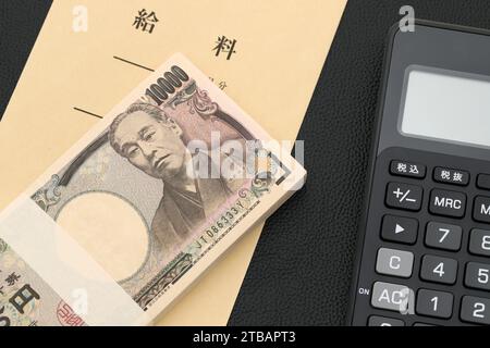 Japanischer Gehaltsumschlag und Taschenrechner, Übersetzung: Gehalt, die Banknoten werden auf Japanisch als '10.000 Yen' geschrieben. Stockfoto