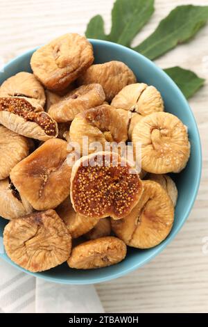 Schüssel mit leckeren getrockneten Feigen und grünem Blatt auf weißem Holztisch, Draufsicht Stockfoto