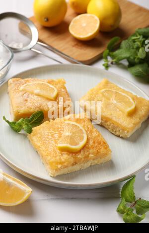 Leckere Zitronenriegel und Minzbonbons auf weißem Tisch Stockfoto