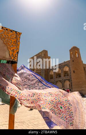 Schöne ethnische Stoffe, die mit dem Wind wehen, neben der alten Madrasah, Buchara, Usbekistan. Selektiver Fokus mit Kopierraum für Text Stockfoto